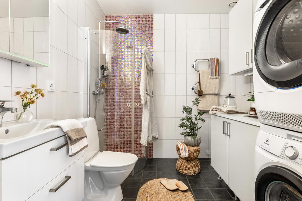 Stort helkaklat badrum med tvättavdelning.