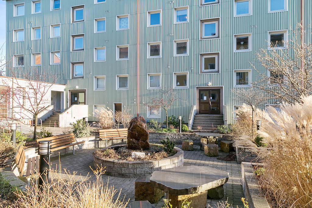 Innergård med bland annat en större gräsyta, planteringar och sittplatser