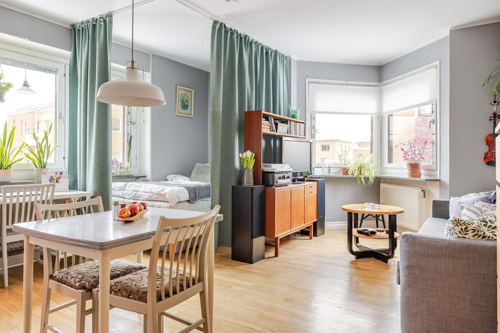 Rymligt vardagsrum med plats för säng, soffgrupp och arbetsplats.