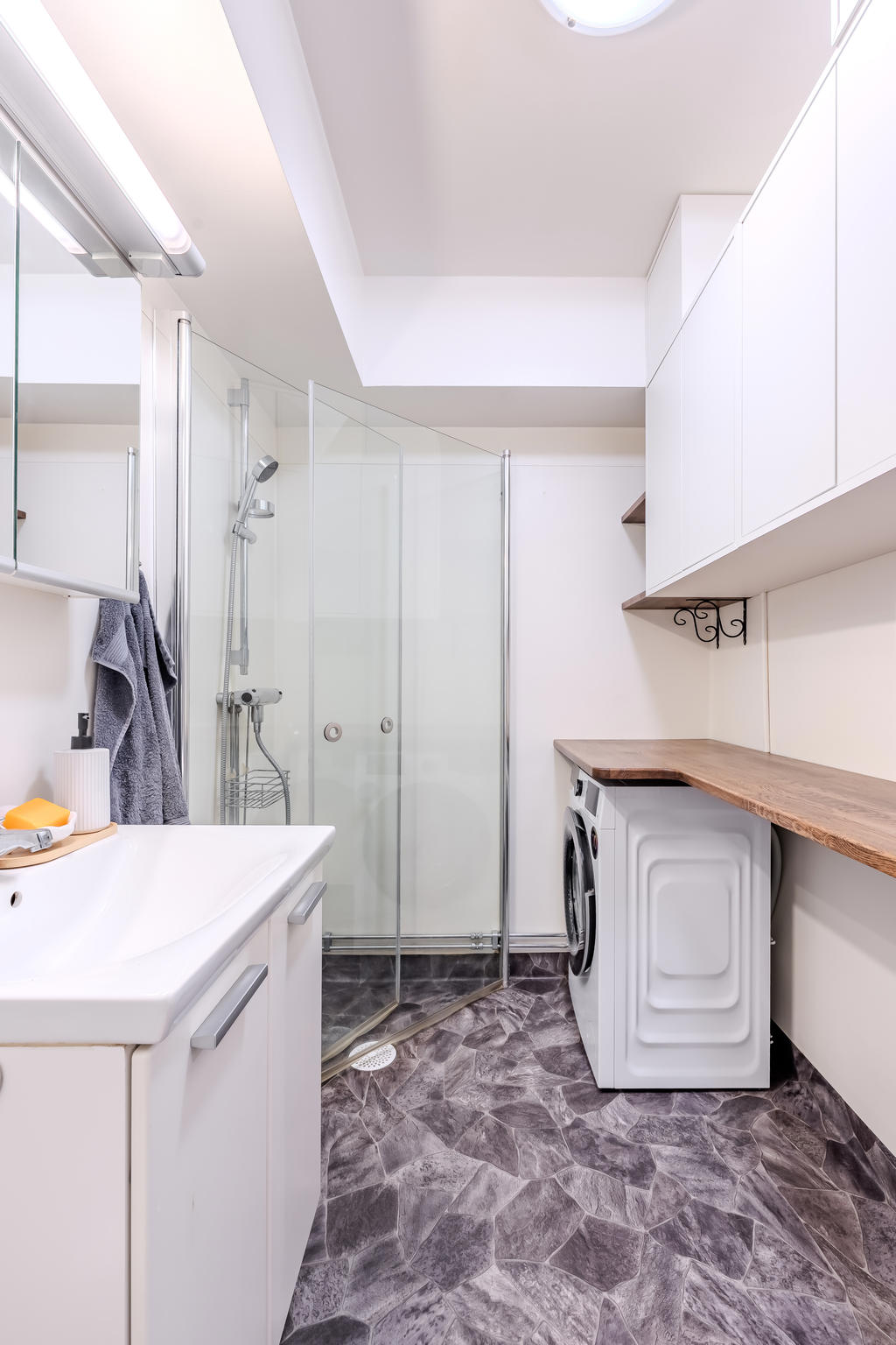 Badrummet har tvättmaskin med praktisk arbetsyta ovanför. 