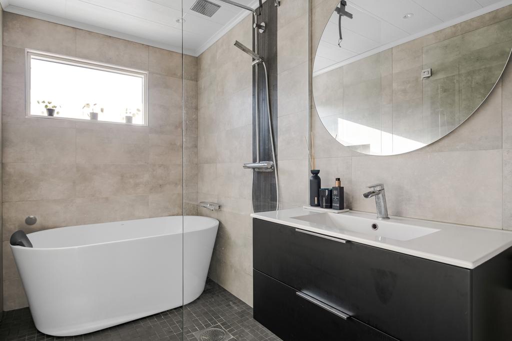 Badrum med både dusch och badkar bakom rejäla duschväggar. 