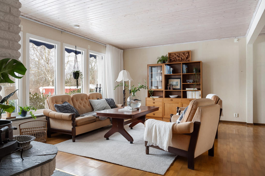 Vardagsrum med öppen spis och vy mot poolen.