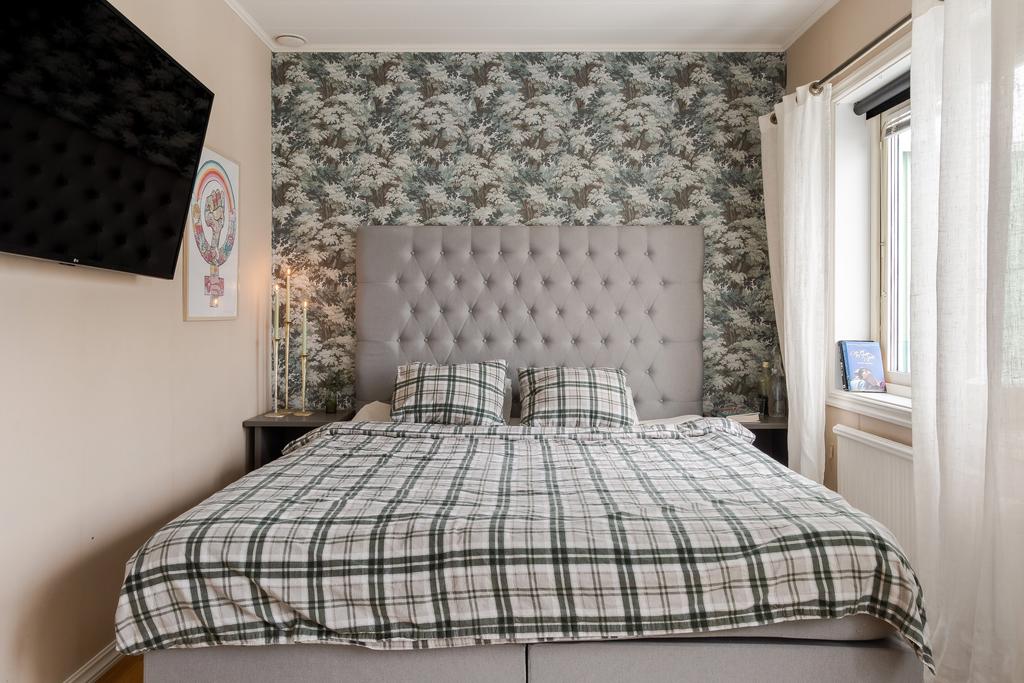 Sovrum med mönstrad fondvägg och plats för dubbelsäng.