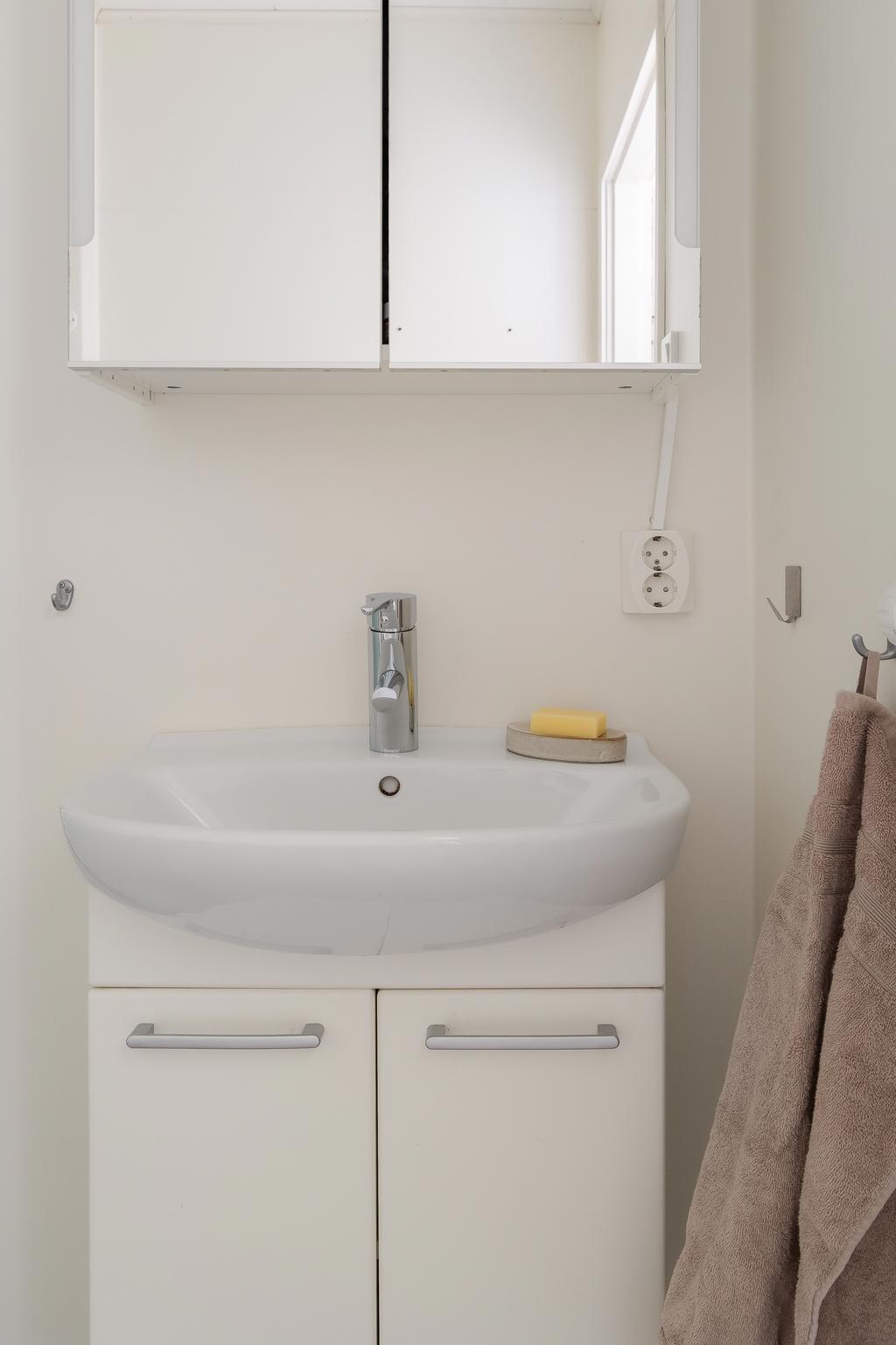 Badrum med förvaring i kommod och spegelskåp.