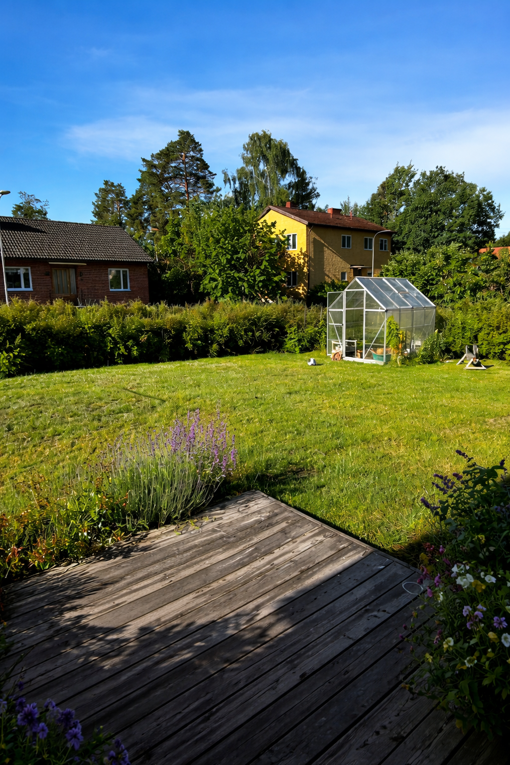 Plan, lekvänlig gräsmatta och växthus på tomten