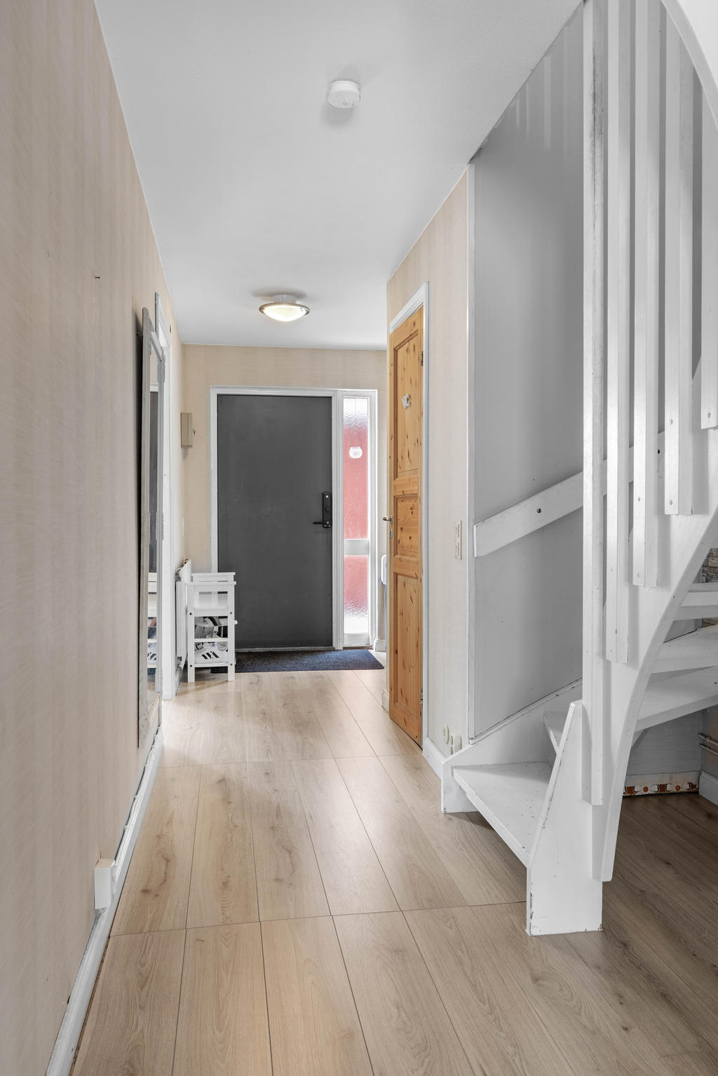 Hall med nyare golv, gästtoalett samt trapp till övervåning. 