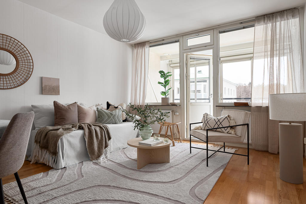 Ljust vardagsrum med parkettgolv och utgång till balkong