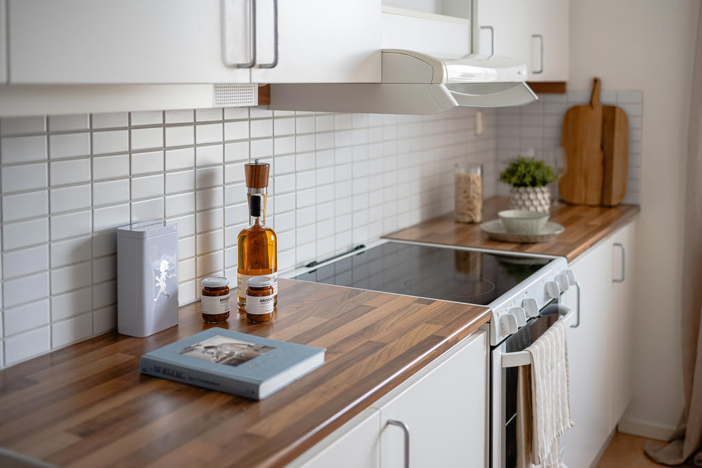 Fräscht kök med vita luckor, kakel och en fin bänkskiva i laminat.