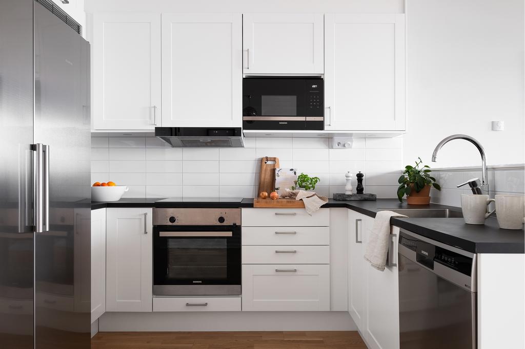 Köket i klassiskt vitt blir en abstrakt kontrast till den svarta bänkskivan. Alla vitvaror är uppgraderade så standarden är högre än orginal.