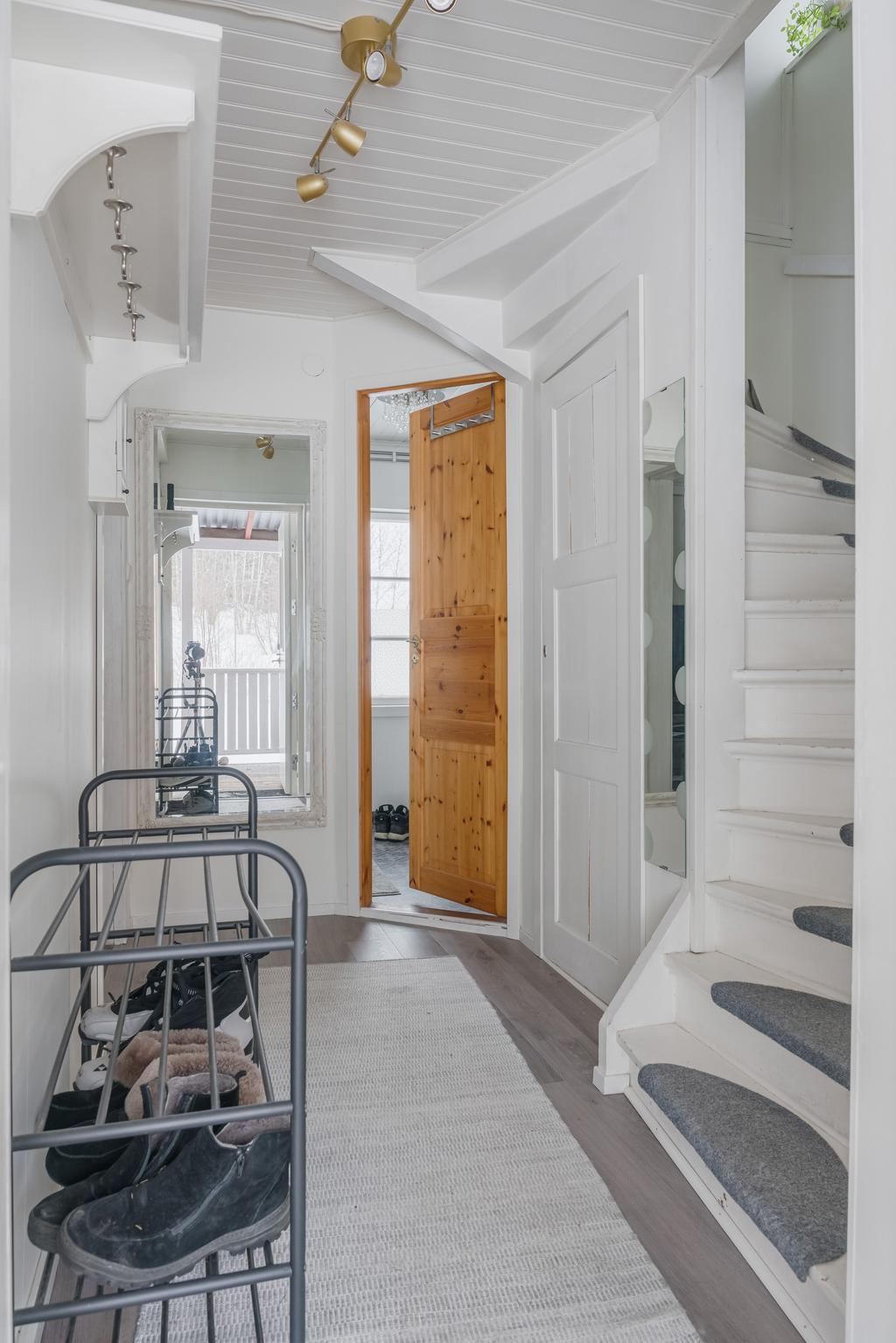 Välkomnande hall med möjlighet till avhängning. Under trappen finns även praktiska förvaringsutrymmen.