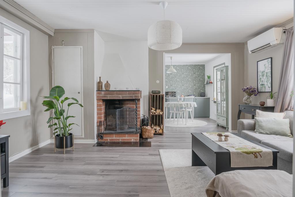 Ljust och öppet vardagsrum med fint ljusinsläpp och en centralt placerad öppen spis som skapar både värme och karaktär.
