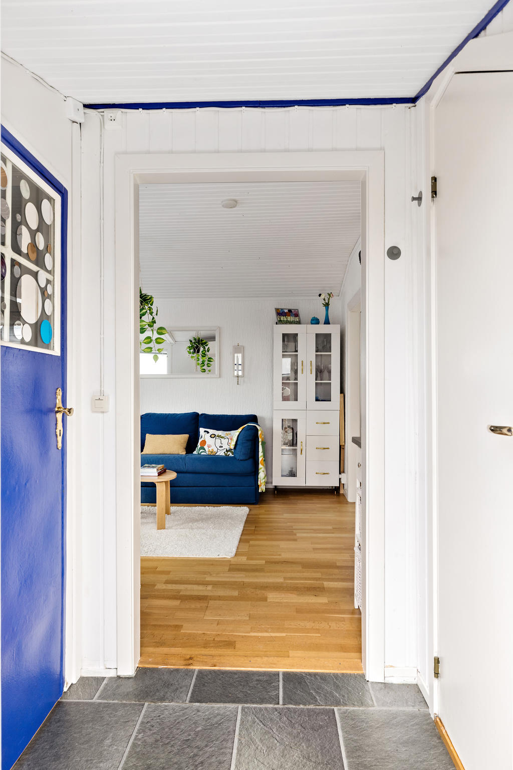 Entréhall med klickgolv. bakom den blå dörren finner ni duschen och bakom den via toaletten