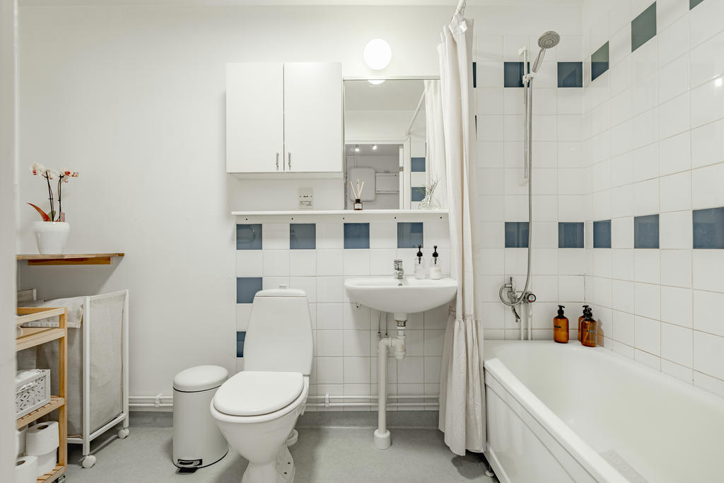 Rymligt badrum utrustat med wc, handfat, badkar, tvättmaskin och avlastningsyta.