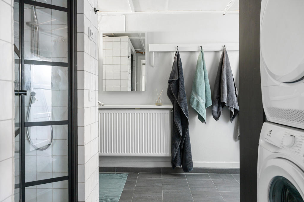 Del av badrum med dusch, handfat med kommod och tvättmaskin