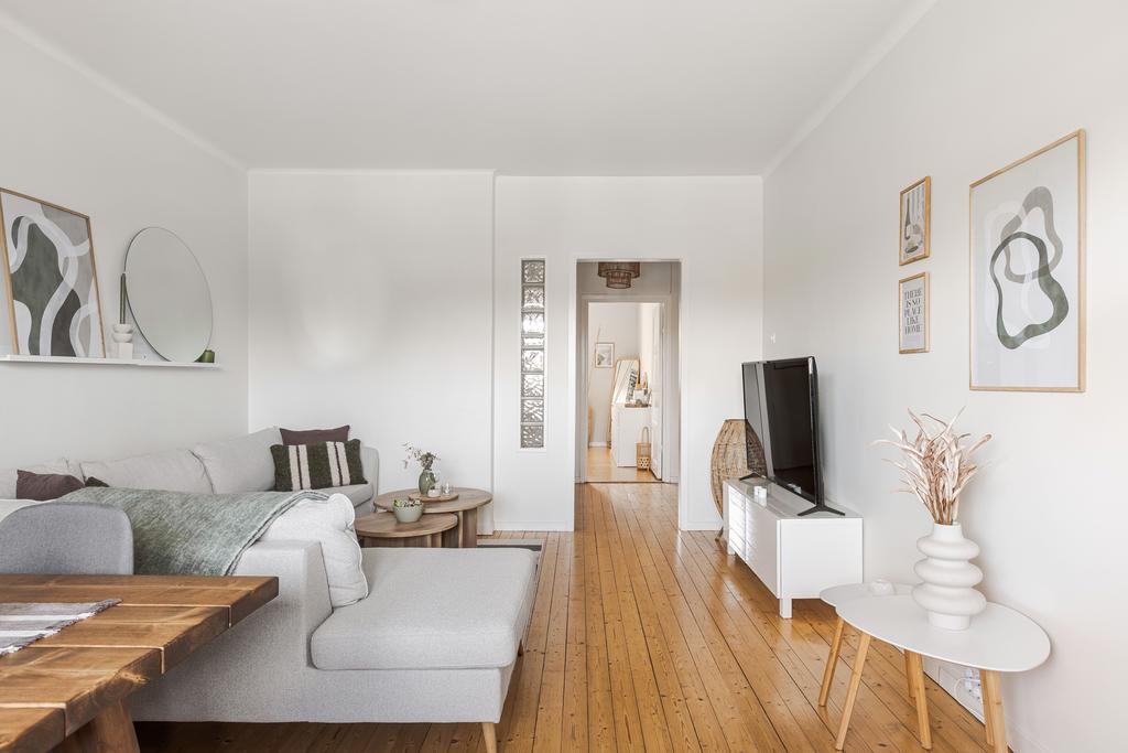 Vardagsrum med fint trägolv med vy mot hall och sovrum