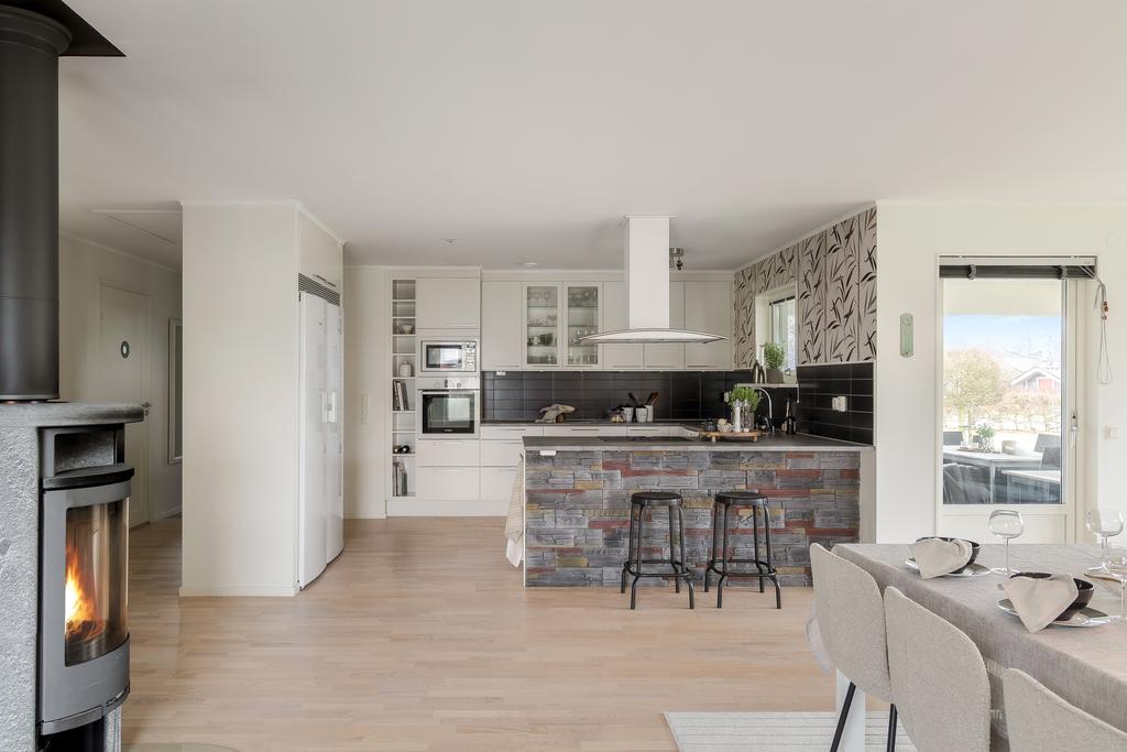 Den öppna planlösningen mellan kök och vardagsrum ger en social och trivsam atmosfär där både vardag och fest får plats.