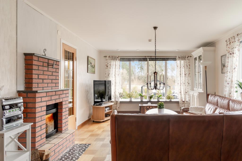 Vardagsrum med stora fönster som släpper in ljus. På golvet ligger en fin ekparkett.