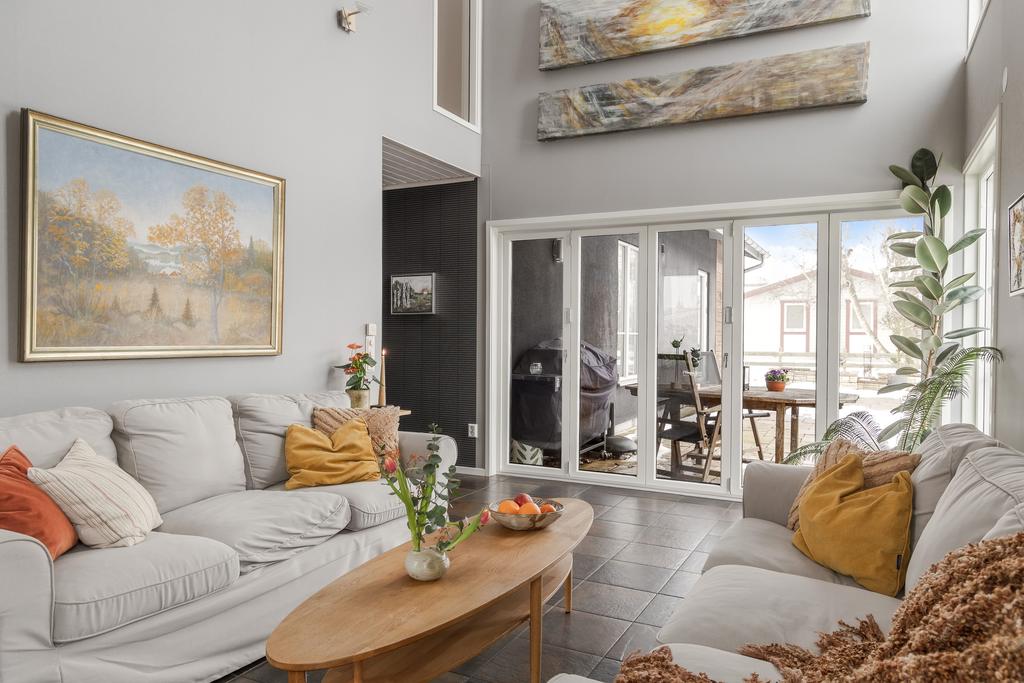 Vardagsrum med högt till tak och ett otroligt ljusinsläpp från de stora fönstren. På golvet ligger en fin klinker i jordnära toner.