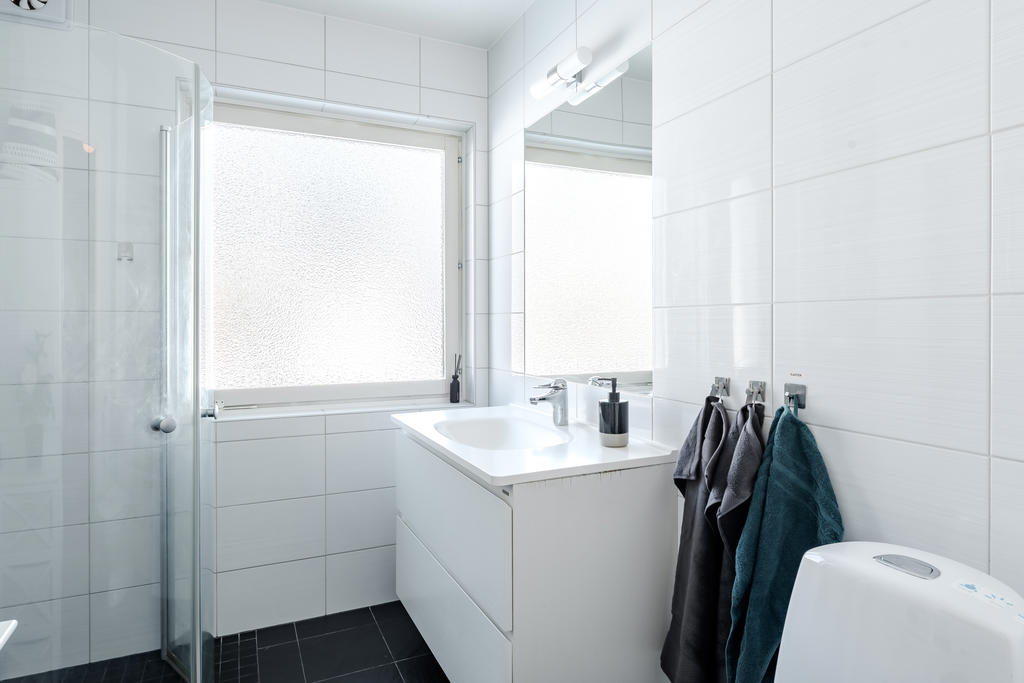 Badrummet har helkaklade väggar, klinkergolv samt stort fönster.