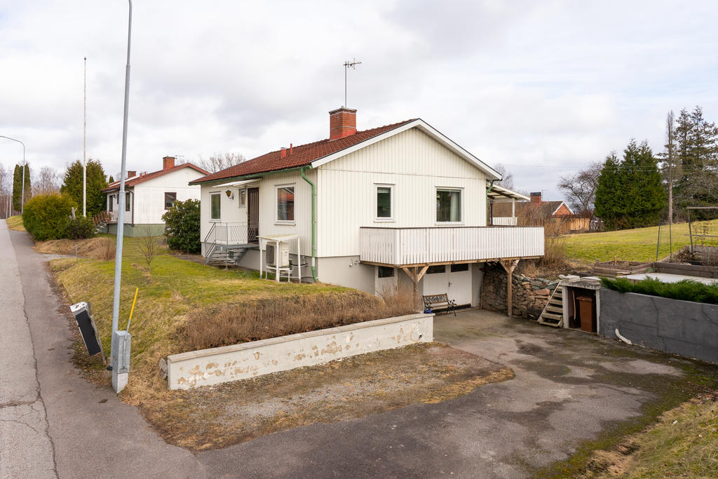 Asfalterad uppfart med garage i huskroppen.