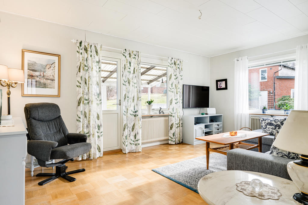 Ljust och hemtrevligt vardagsrum med utgång till altan under tak.