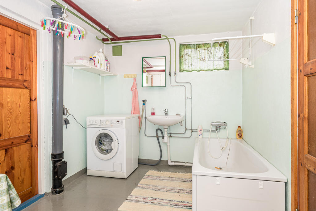 Tvättrum med tvättmaskin, handfat och badkar.