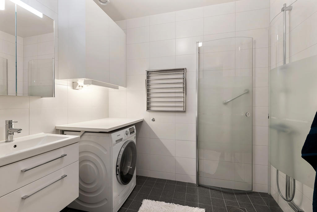 Helkaklat badrum med kombinerad tvättmaskin och torktumlare.