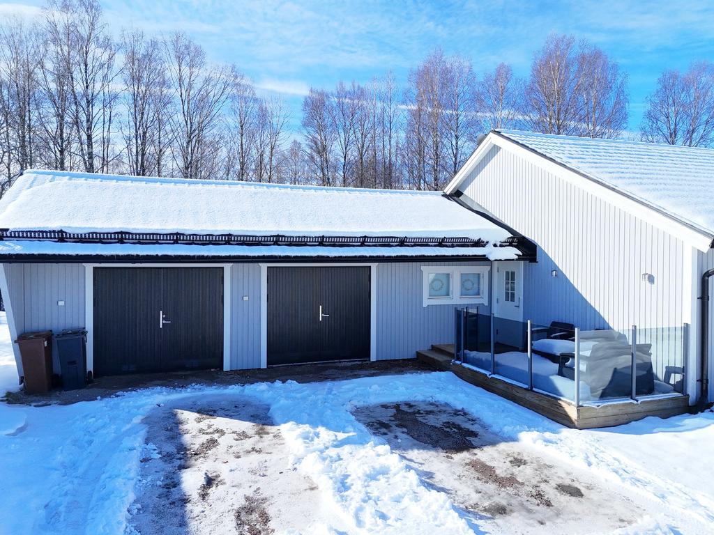 Dubbelgarage och uteplats med morgonsol.