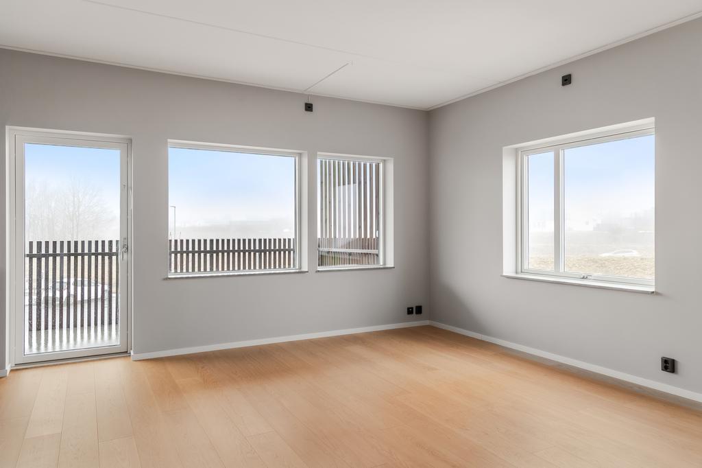 Lättmöblerat allrum med fönster i två väderstreck.