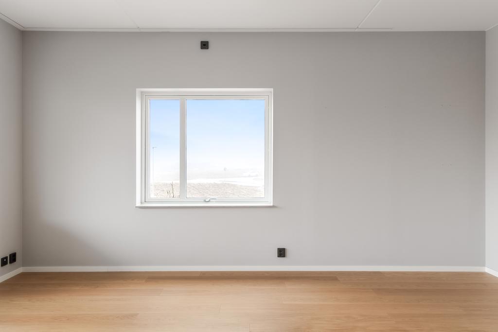 Rummet präglas av ljusa väggar och enhetligt golv.