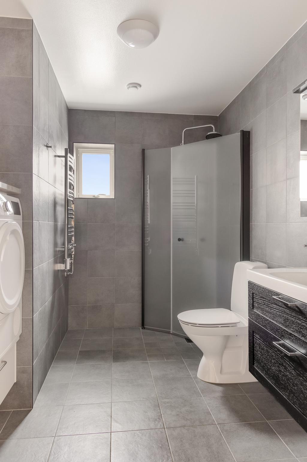 Badrum med duschhörna, wc och arbetsbänk ovan tvättutrustning.