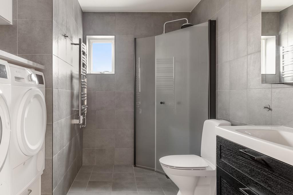 Helkaklat badrum med dusch, tvättmaskin och torktumlare.