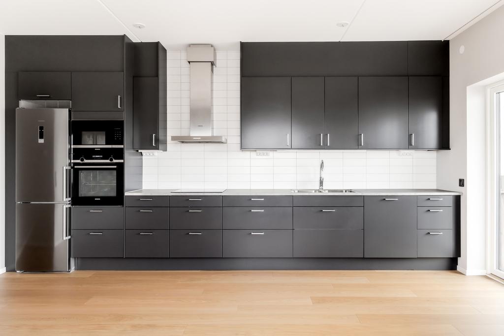 Kök med mörk skåpinredning, bra arbetsytor och full maskinell utrustning.