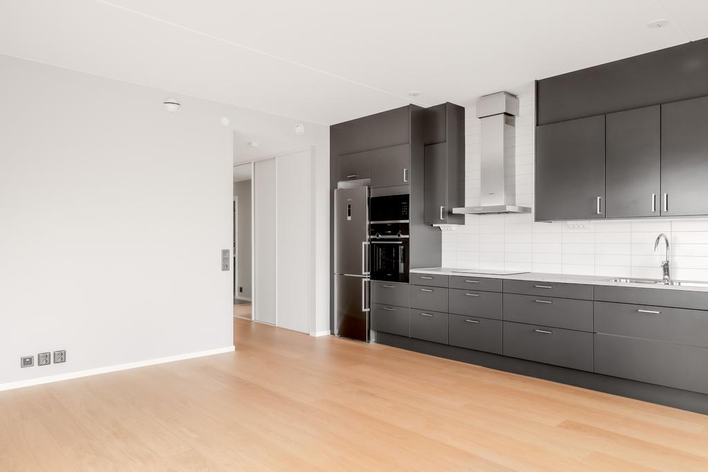 Öppen vy mellan kök och vardagsrum som skapar en sammanhängande och lättmöblerad yta.