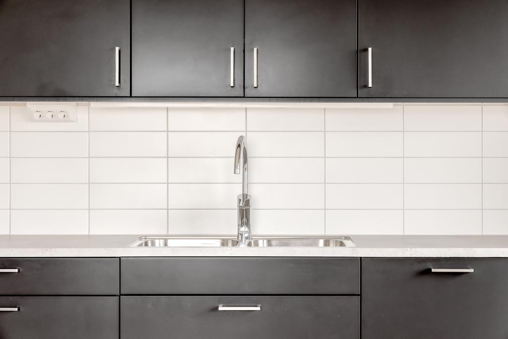Detaljbild av kökets arbetsdel med diskho, kaklat stänkskydd och god förvaring.