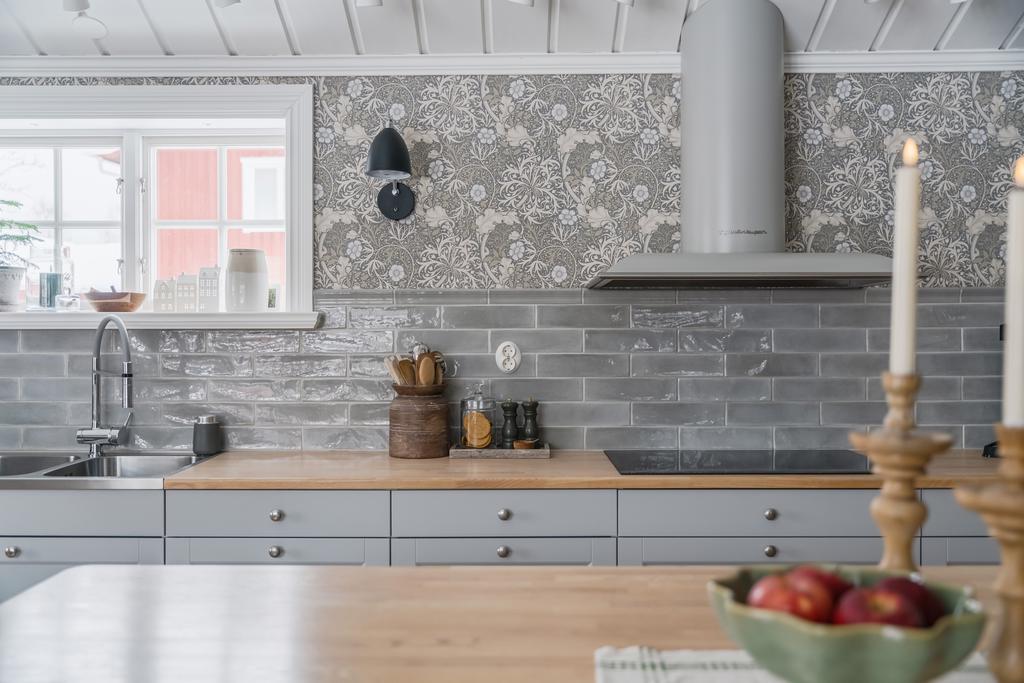 Kakel och tapet är noggrant utvalda och samspelar fint med kökets färgsättning, vilket ger ett varmt och ombonat intryck.