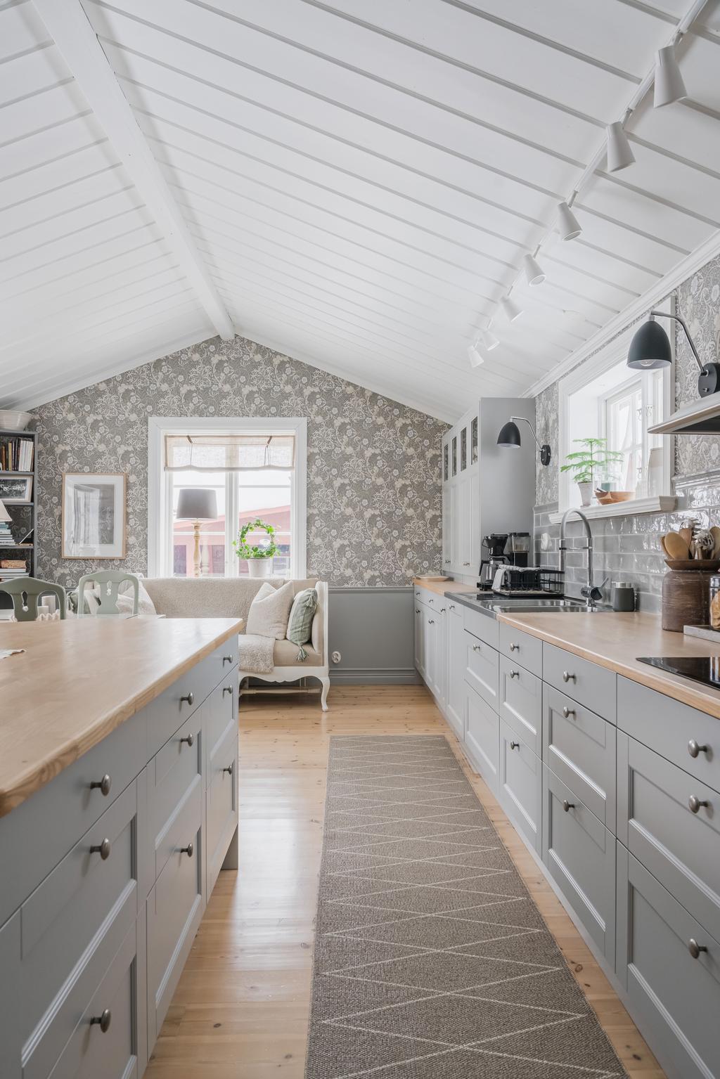 Ett ljust och luftigt kök där det höga taket och fönstersättningen skapar en härlig rymd och trivsam atmosfär.