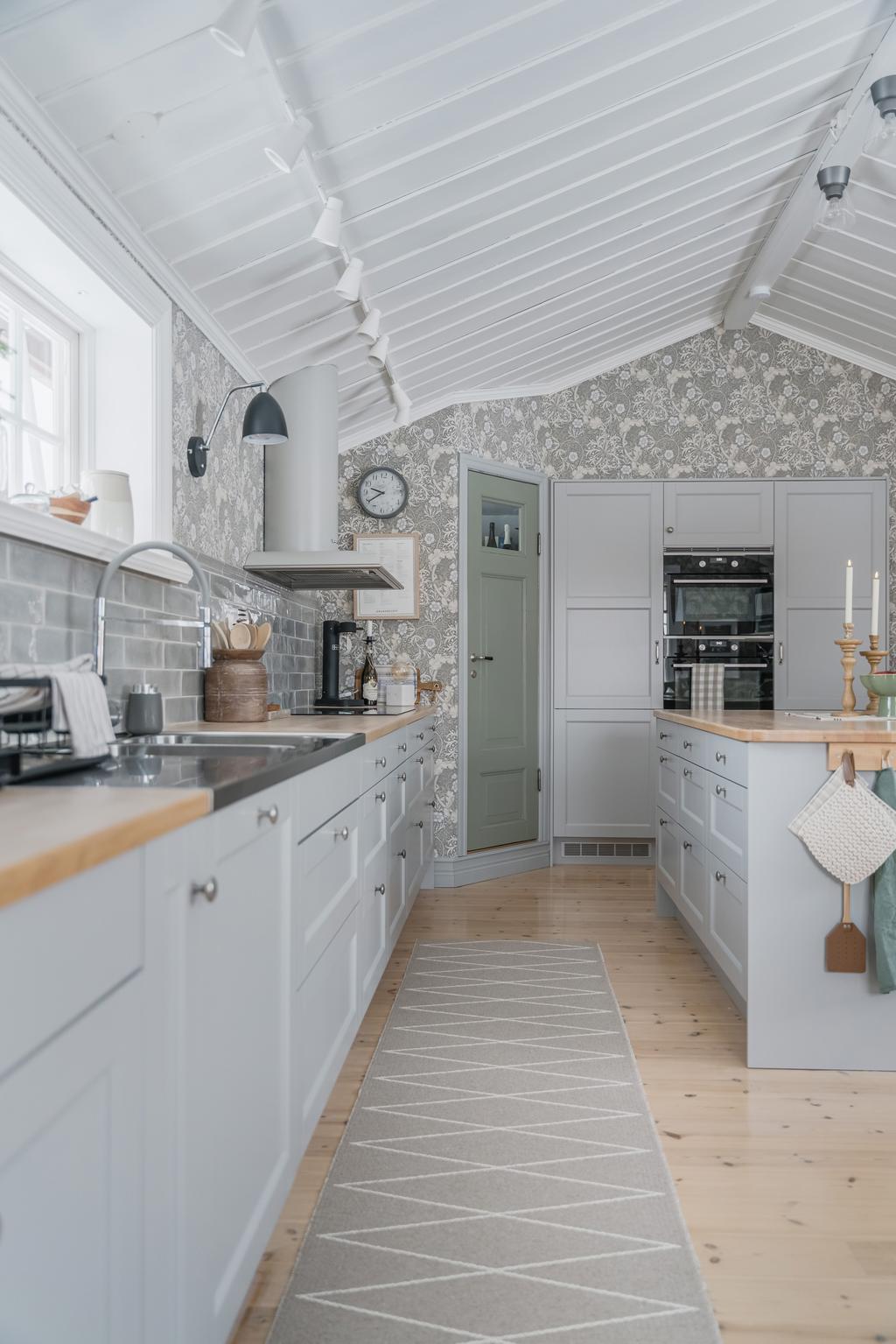 Ett platsbyggt skafferi ger generösa förvaringsmöjligheter och bidrar till kökets genomtänkta funktion.