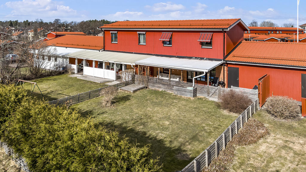 Baksidan med stor uteplats samt lättskött trädgård