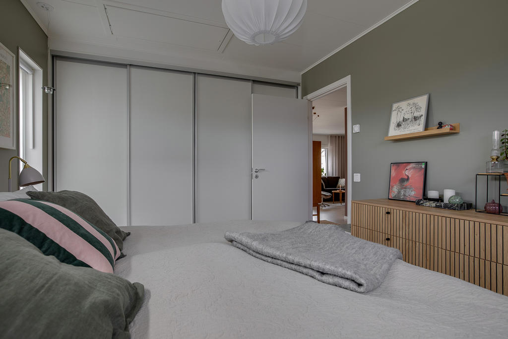 Sovrum med hel garderobsvägg och ett Elfa-System bakom skjutdörrarna. 