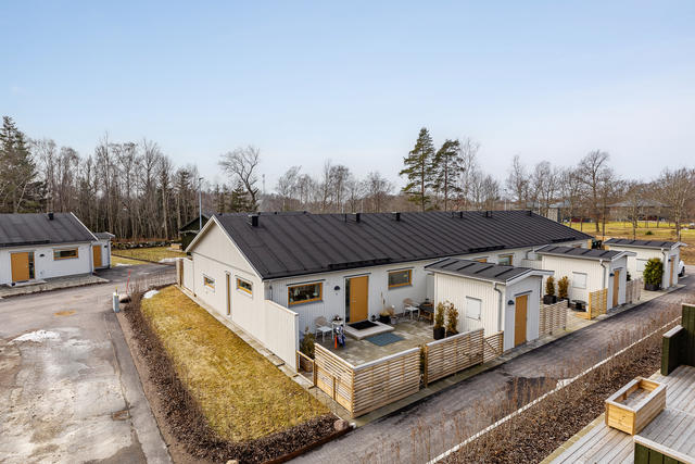 Entrésidan med stenläggning framför och ett vidbyggt förråd som är isolerat. 