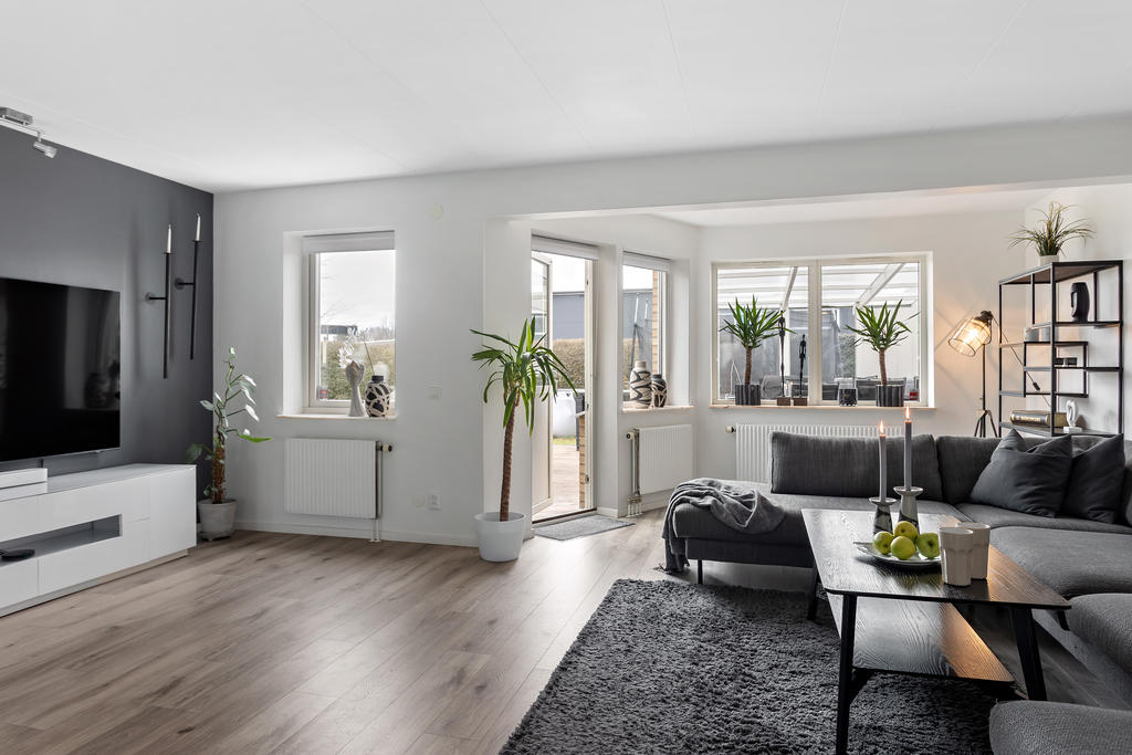 Vardagsrum i vinkel med utgång till trädecks-altan och trädgården