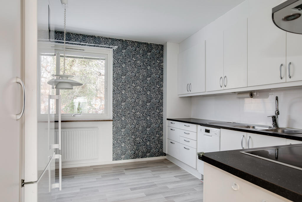 Ljust och stilrent kök med blommig accentvägg