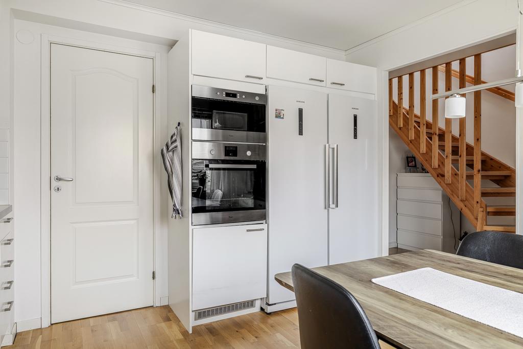 Ingång til tvättstuga med tvättmaskin, torkskåp och handfat/arbetsyta.