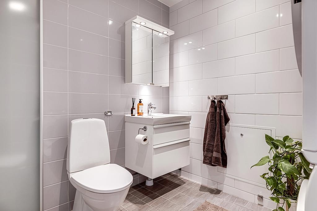 Helkaklat badrum i ljusa fina klassiska toner. Dusch med vikväggar som maximerar golvytan. 