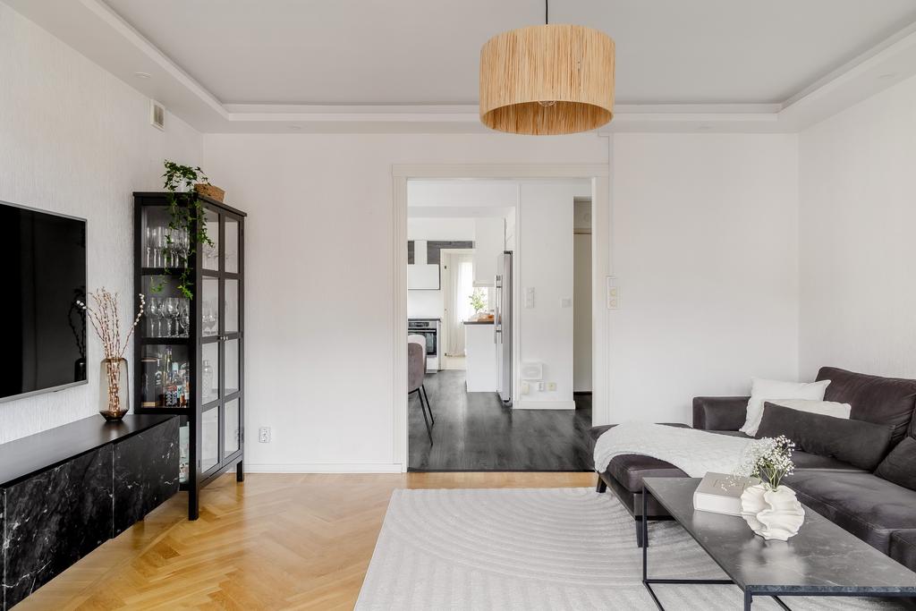 Vardagsrummet är lättmöblerat och här kombineras ljusa väggar med tidlös fiskbensparkett 