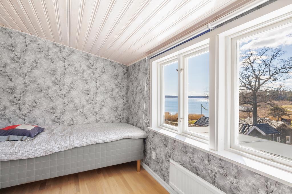 Mindre sovrum med vitkalkat ekgolv, tapetserade väggar och vitlaserat tak.