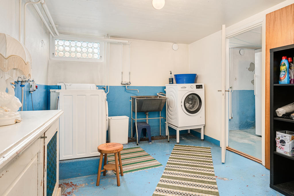 Tvättrum med tvättmaskin och torkrum-källarplan.