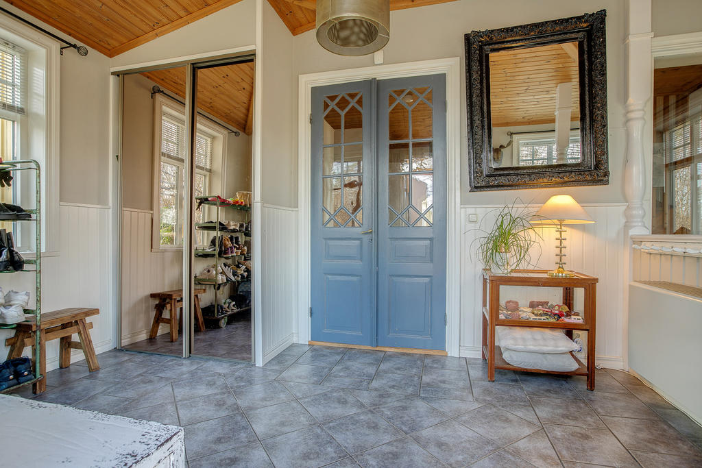 Stor bred entréhall med trappa till källaren och dörr in till innerhallen