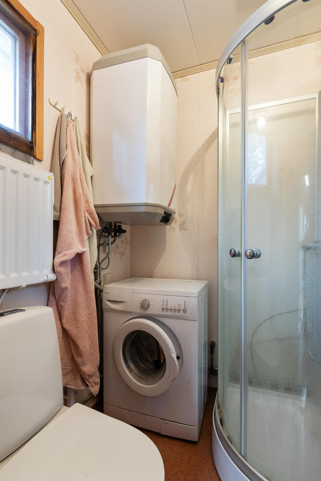 Badrum med duschkabin, WC, handfat och tvättmaskin. 